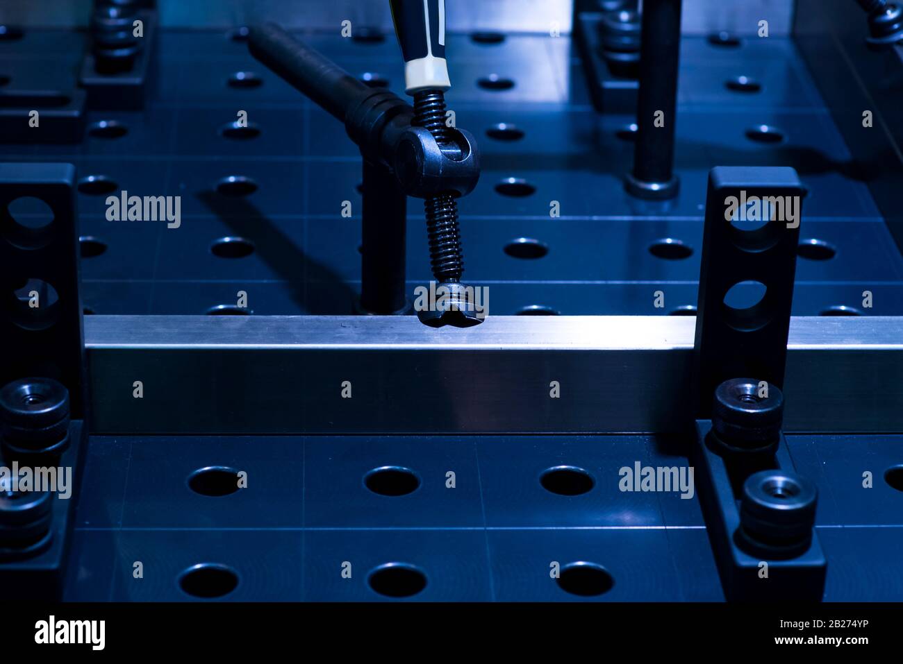 Neue verchromte Befestigungslasche. Zubehör für einen Mechaniker und eine Metallverarbeitung. Dunkler Hintergrund. Stockfoto