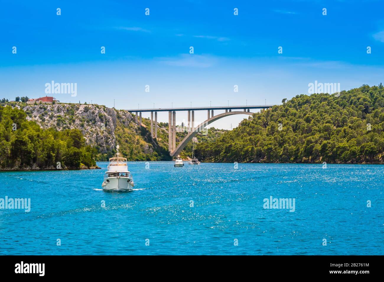 Touristenboote im Krka National Park, Kroatien. Sibenik-Brücke über den Fluss Krka mit klarem Wasser und blauem Himmel an einem sonnigen Tag. Stockfoto