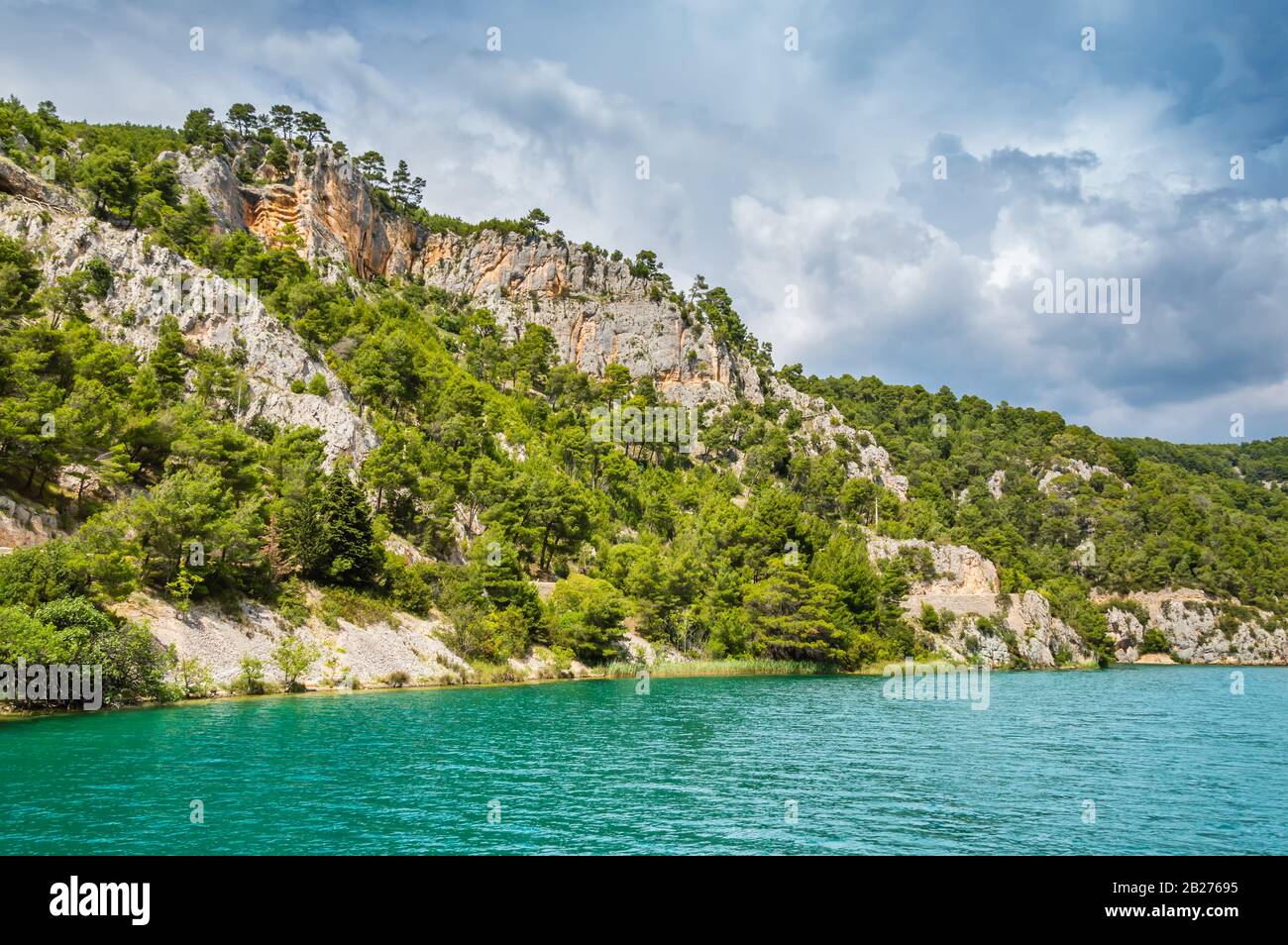 Grüne Hügel mit Wald rund um den Fluss Krka im wunderschönen Nationalpark Krka, Kroatien. Touristische Boote fahren auf dem Fluss entlang, um Skradinski buk waterfal anzukommen Stockfoto