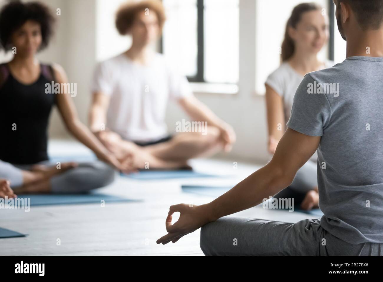 Yoga-Trainer und eine Gruppe von Menschen meditieren zusammen Nahbild Stockfoto