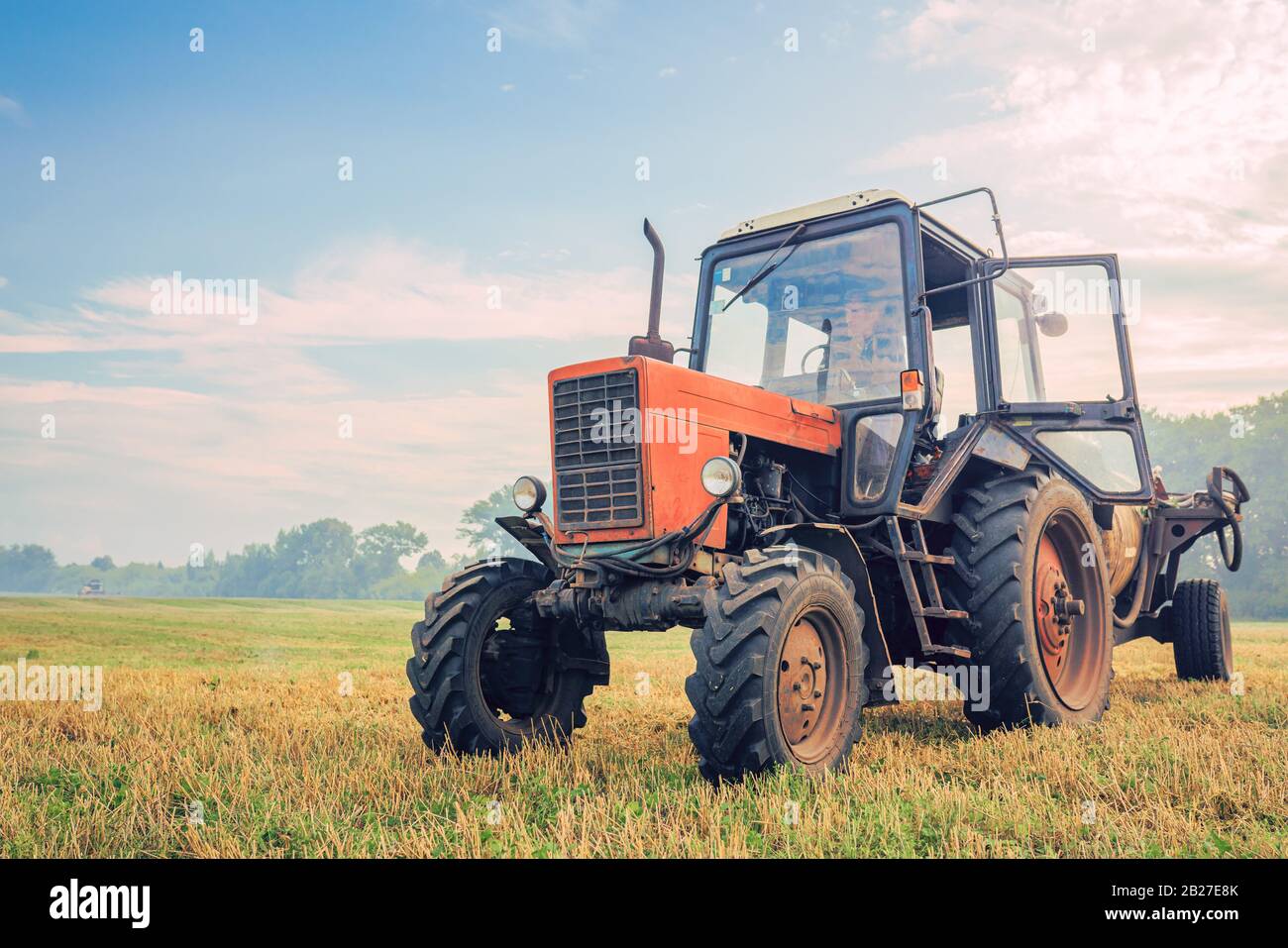 Alter Traktor düngt auf dem Feld an einem schönen blauen sonnigen Tag Stockfoto
