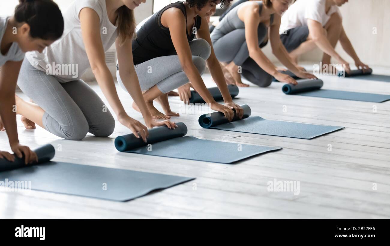 Multiethnische Leute, die Matten falten, haben die Yoga-Sitzung im Sportclub beendet Stockfoto