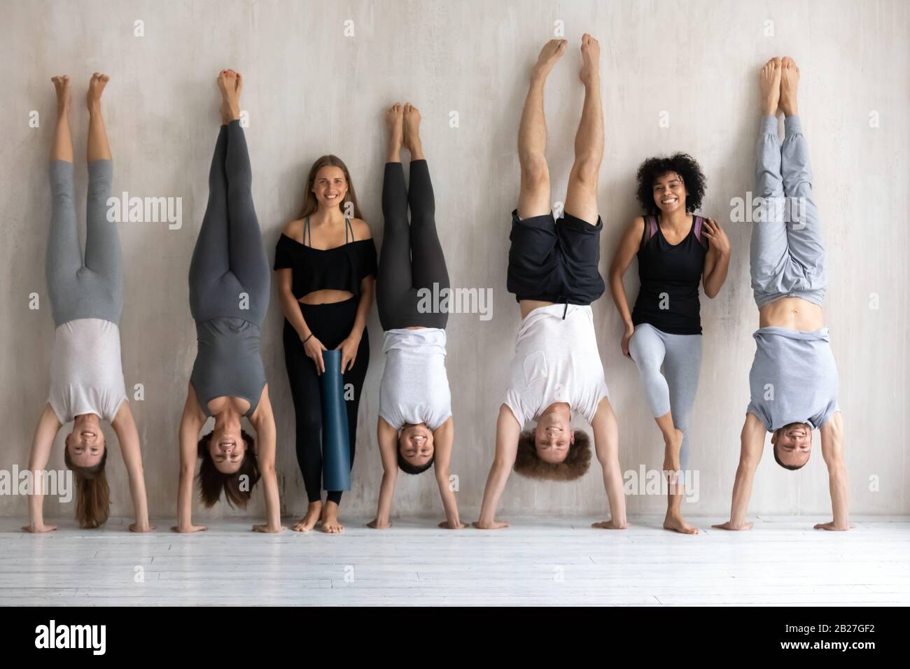 Multiethnische, starke Sportive in der Sportbekleidung, die in der Nähe der Wand stehen Stockfoto