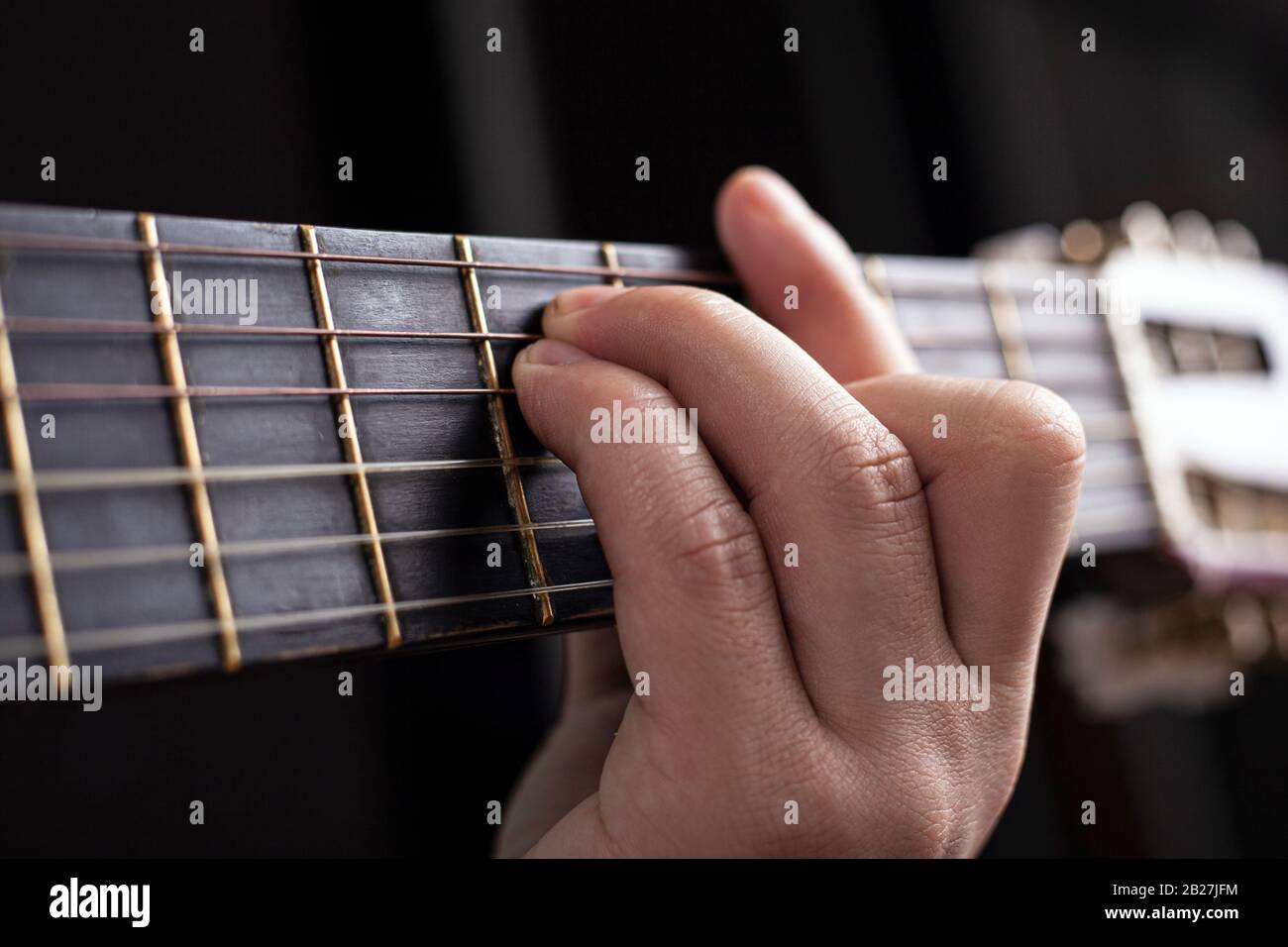 Die männliche Hand spannt einen akustischen Gitarrenakkord und lernt, das Instrument aus nächster Nähe zu spielen. Stockfoto