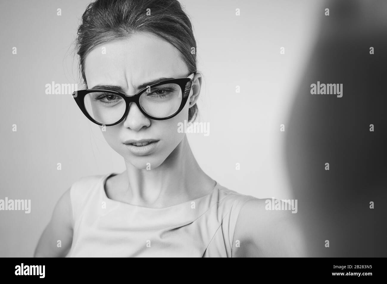 Das Porträt der wütenden Frau, die eine Brille trägt, gibt einen Ohrfeigen, das Mädchen trifft die Kamera Stockfoto