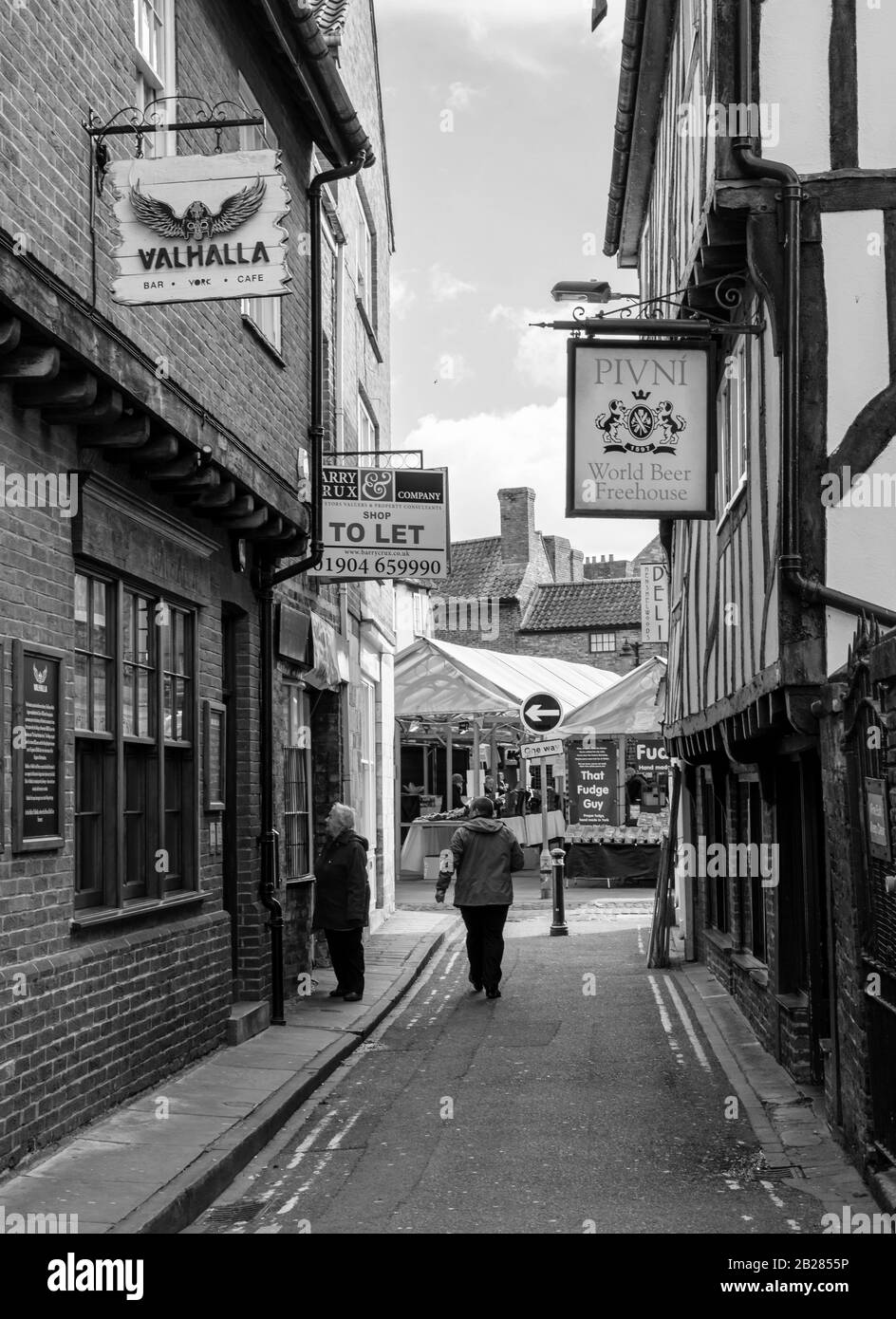 Eine enge York Snickleway, Patrick Pool, führt zum Shambles Market. Boilings sind auf jeder Seite und eine Frau in einem Schaufenster. Stockfoto