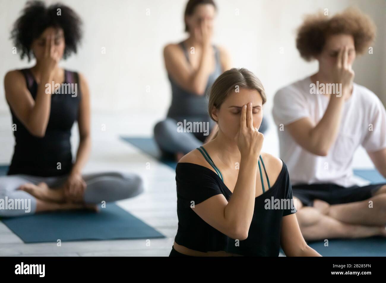 Gruppe von multiethnischen Menschen, die Yoga-Übungen durchführen Alternate Nasenatmung Stockfoto