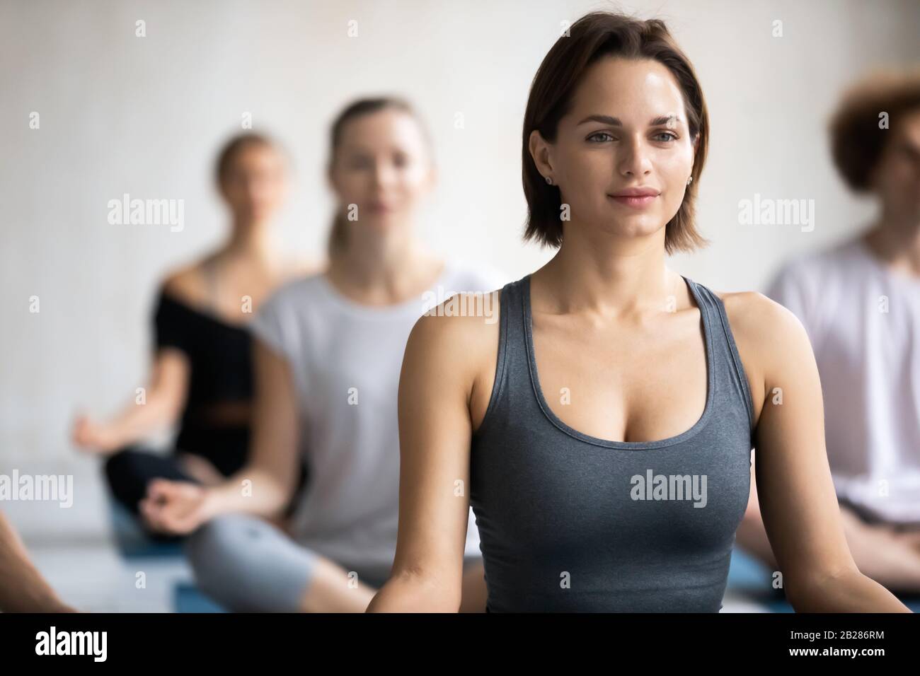 Jahrtausende weibliche Trainerin meditiert mit einer Gruppe von Menschen Stockfoto