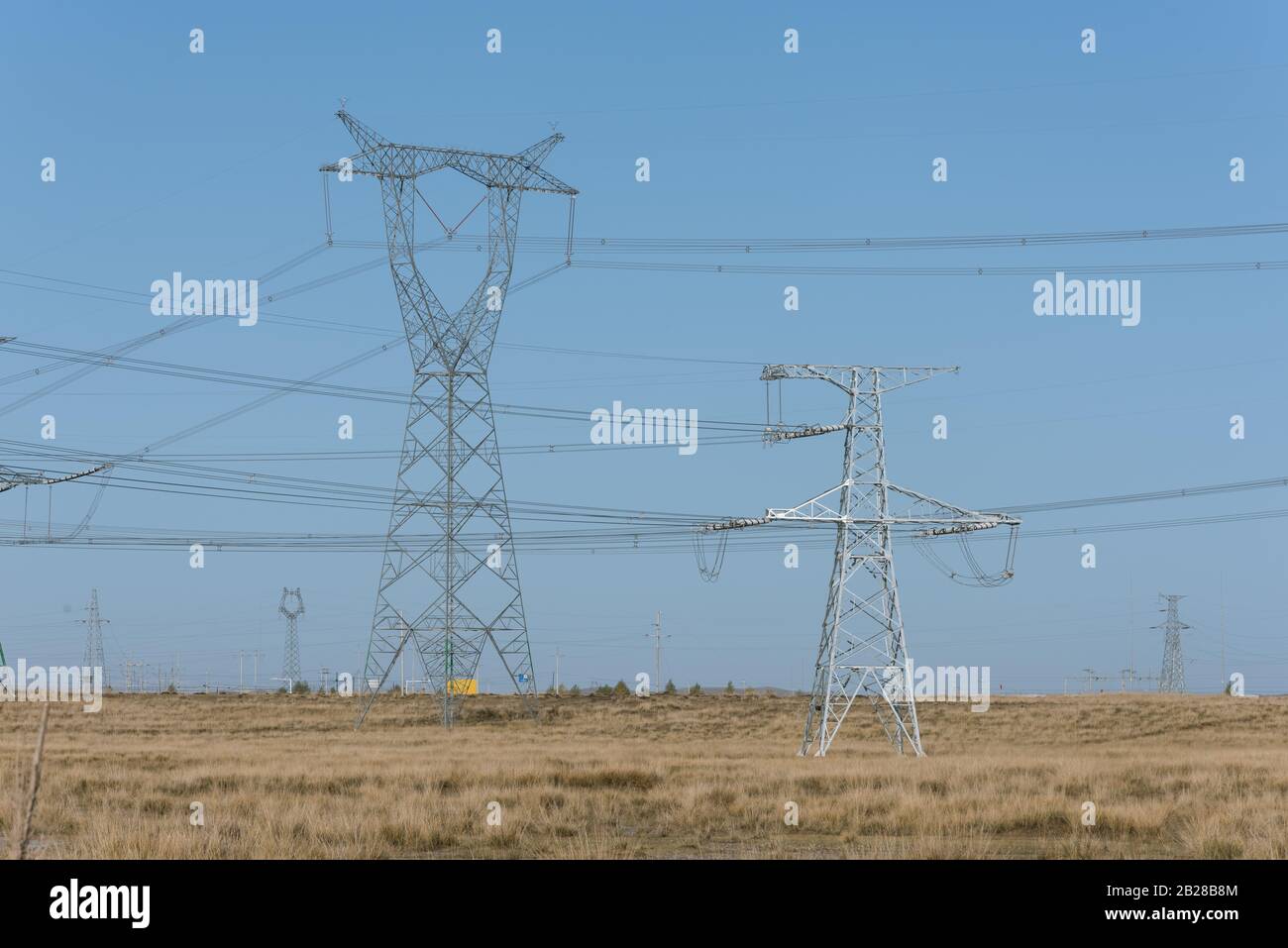Hochspannungs-Pylone auf trockenem Grasland Stockfoto