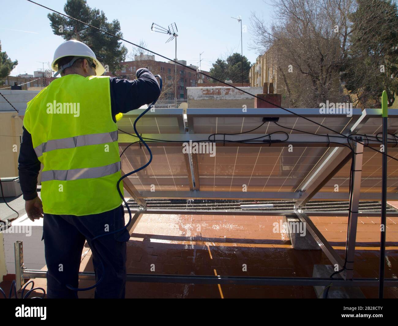 Kaukasischer erfahrener Techniker, der die Solarpaneele repariert und gereinigt. Alternative Stromquelle, nachhaltige Ressourcenkonzeption. Stockfoto