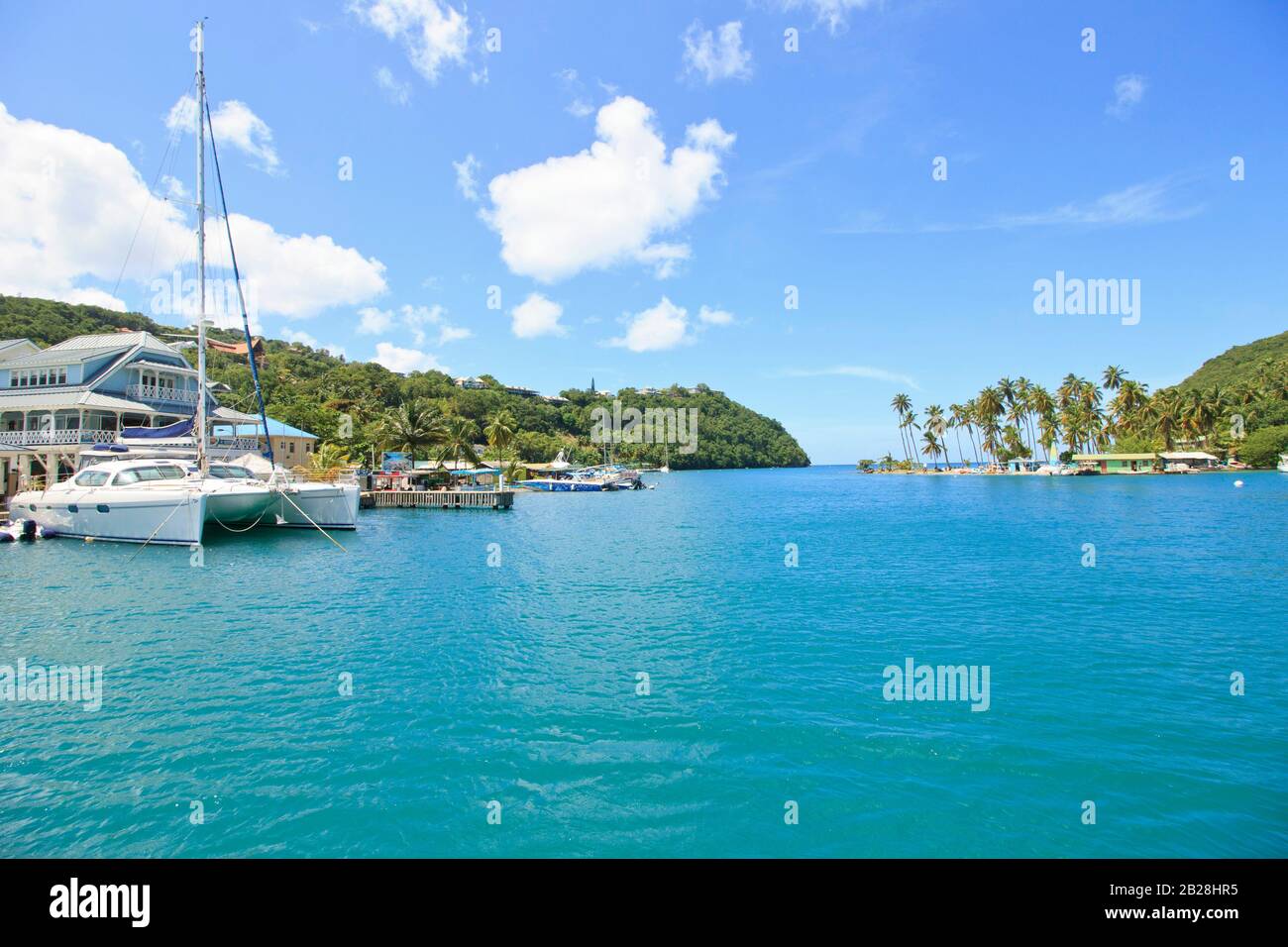 Wunderschönes blaues Meerwasser in der Rodney Bay Marina mit weißen Katamaranen, Jachten, kleiner Bootsanlegelandschaft an einem hellen Tag im sonnigen tropischen Saint Lucia Stockfoto