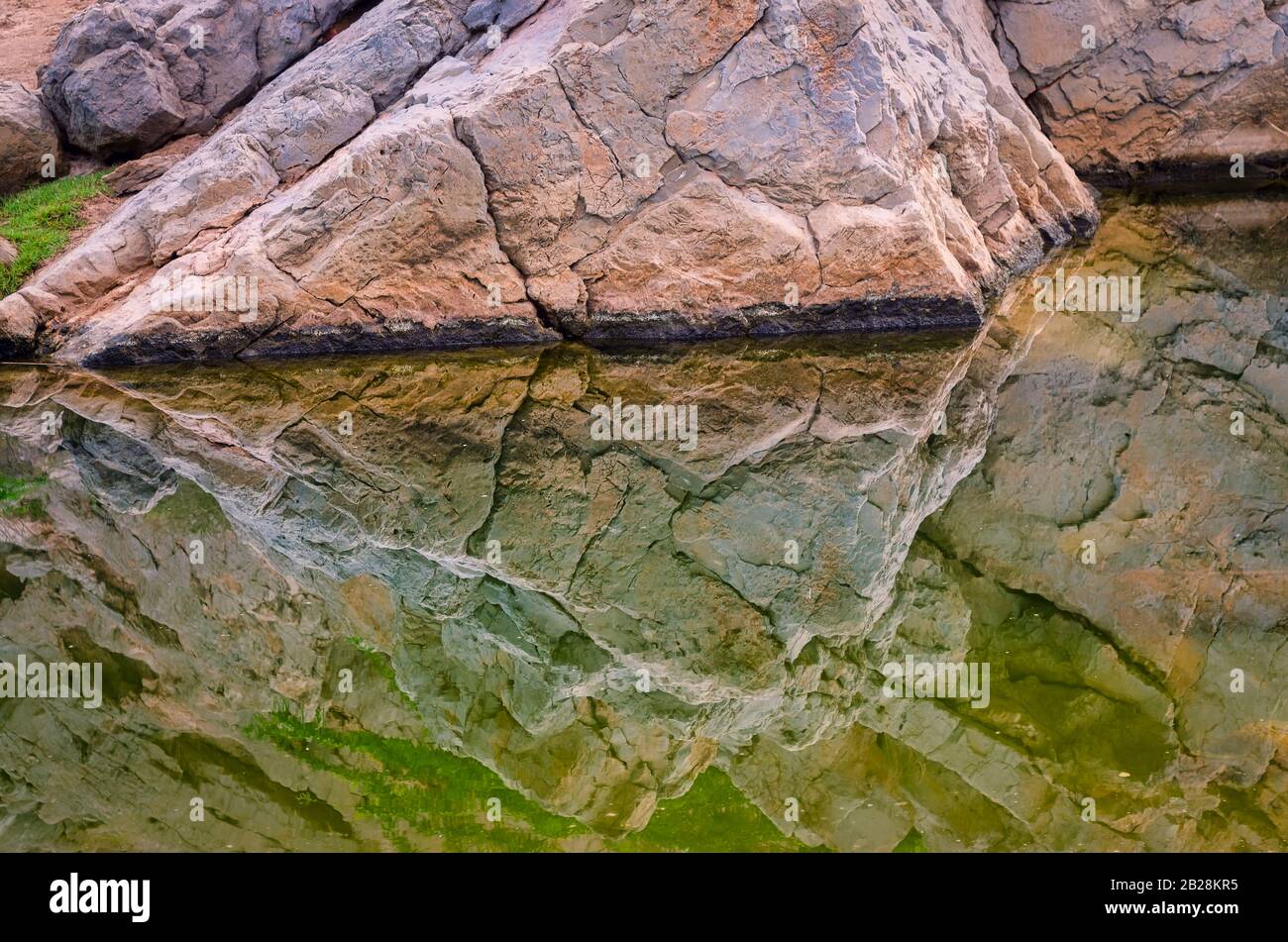 Kalkfelsenberg spiegelte sich in Schmutzwasser wider. Aus Maskat, Oman. Stockfoto