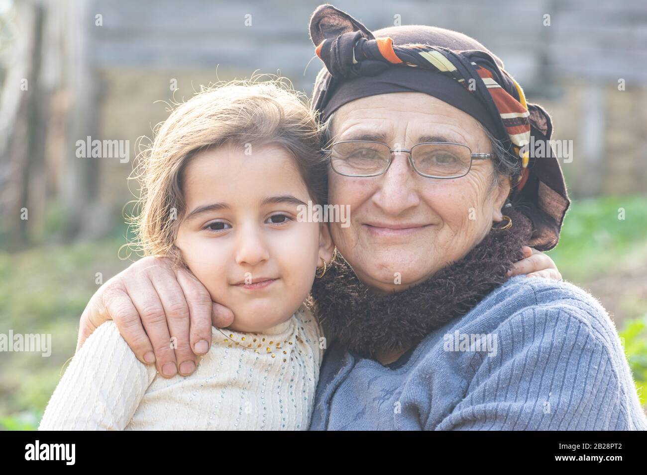 Nahaufnahme des Porträts eines glücklichen kleinen Mädchens mit ihrer älteren muslimischen Großmutter im Garten Stockfoto