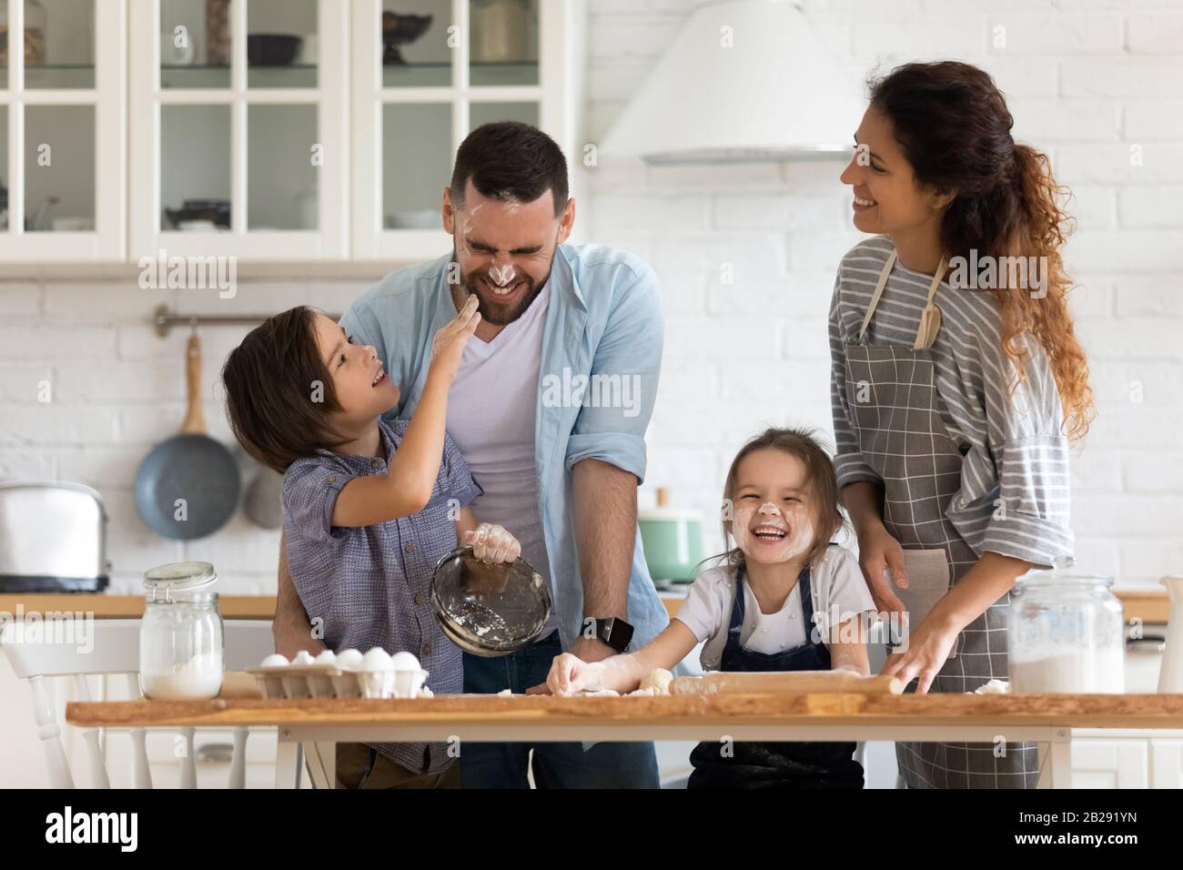 Überfreute Eltern mit kleinen Kindern haben Spaß beim Kochen in der Küche Stockfoto