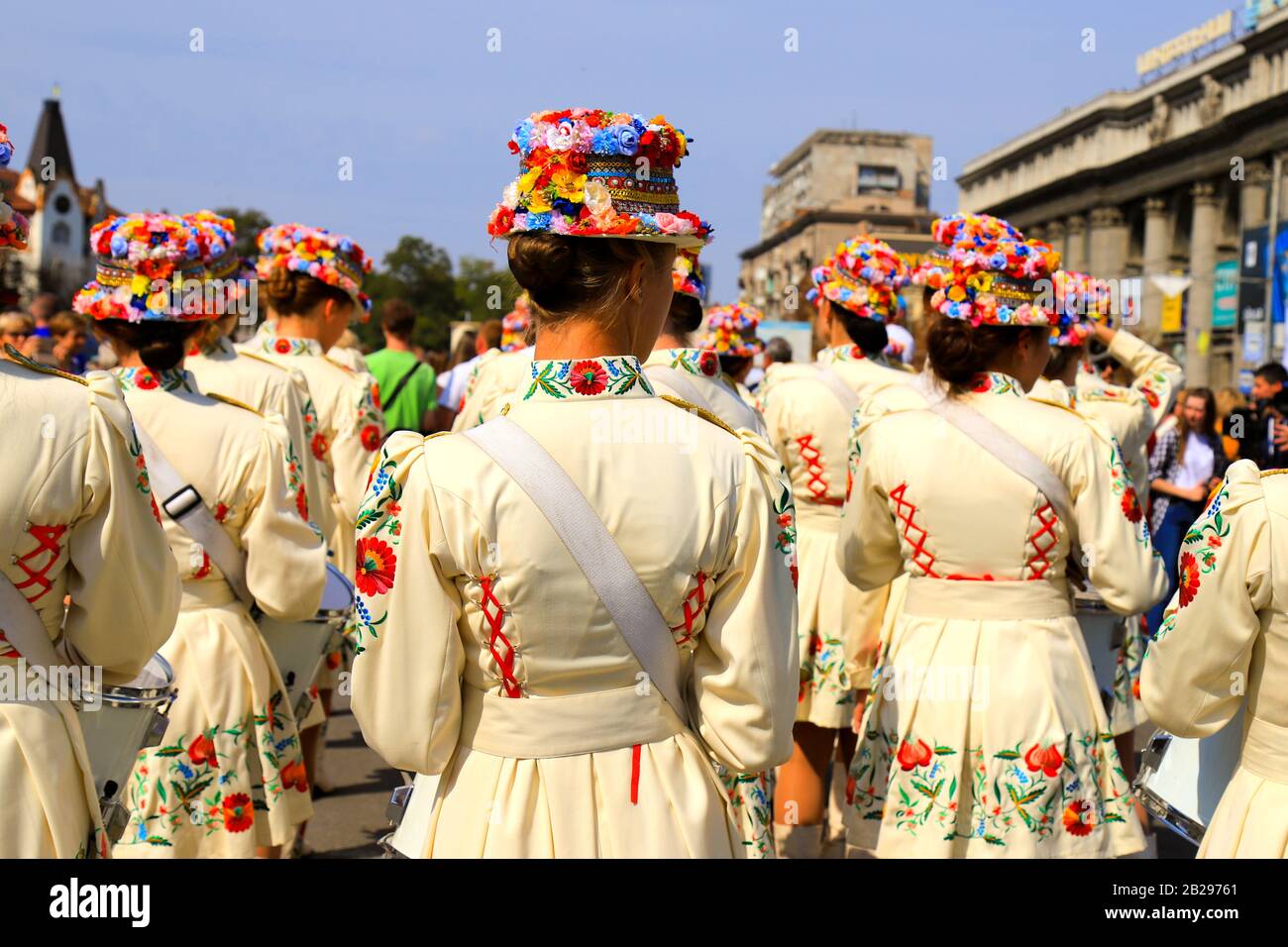 Schlagermädchen in schönen weißen Kostümen und modische Hüte mit leuchtenden Blumen stehen beim Stadtfest, Karneval. Ukrainischer Nationalstil. Stockfoto