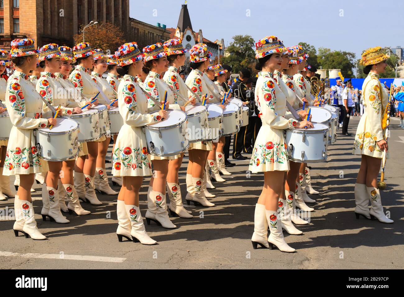 Schlagermädchen in schönen weißen Kostümen und modische Hüte mit leuchtenden Blumen stehen beim Stadtfest, Karneval. Ukrainischer Nationalstil. Stockfoto