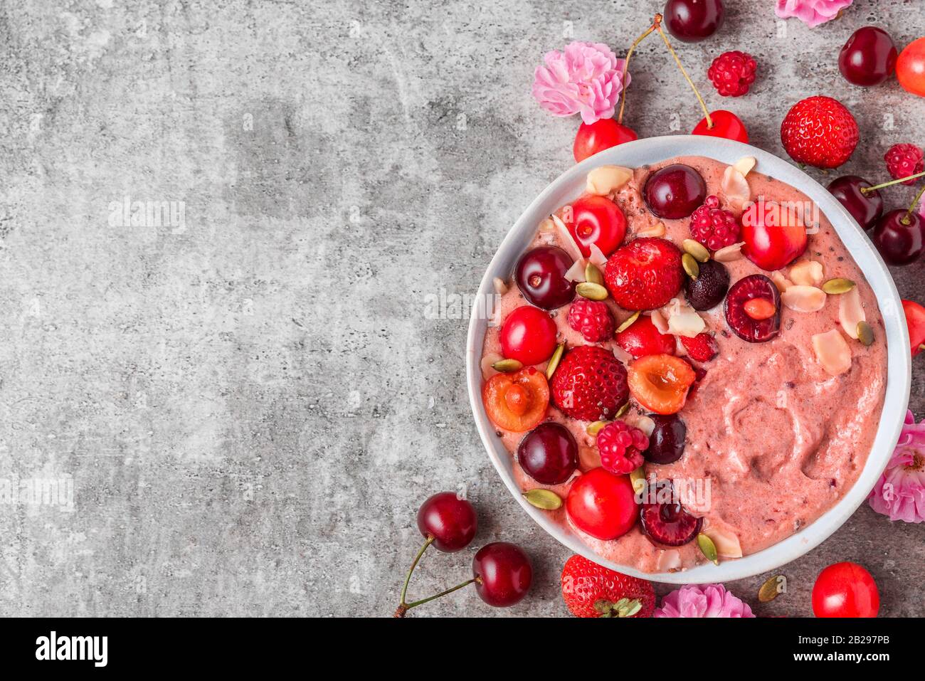 Smoothie-Schüssel oder schöne Creme aus gefrorenen Bananen und Beeren mit frischen Beeren, Nüssen und Samen. Gesundes Frühstück. Draufsicht mit Kopierraum Stockfoto