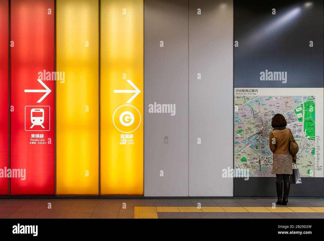 Eine Frau schaut sich eine Karte in Shibuya Station, Tokio, Japan an. Stockfoto