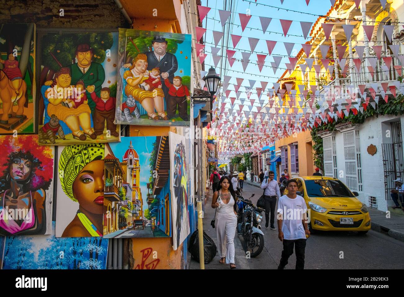 Fußgänger gehen von Gemälden zu Verkauf in einem Künstleratelier im Barrio Getsemaní, Cartagena, Kolumbien Stockfoto