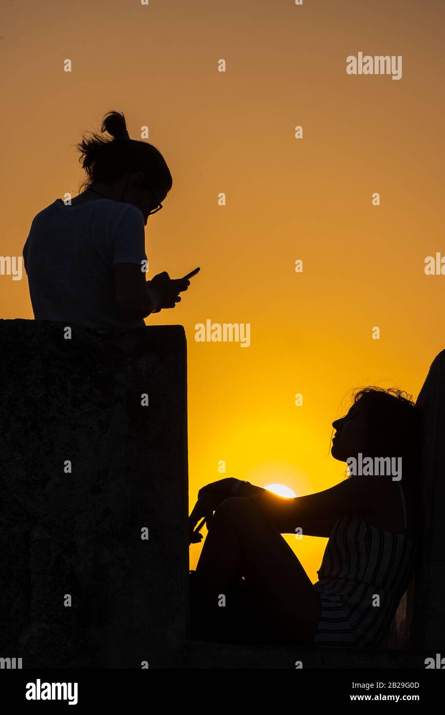 Ein Mädchen hat ihr Foto bei Sonnenuntergang auf einem Smartphone an den spanischen Wänden in Cartagena, Kolumbien aufgenommen Stockfoto