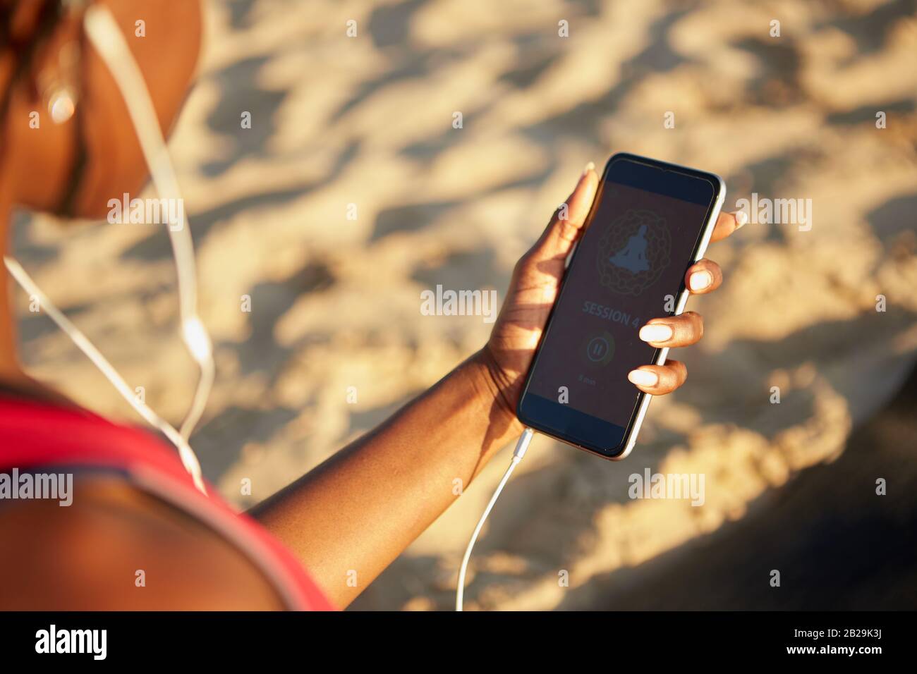 Frau befolgt beim Training am Strand Anweisungen in der mobilen Yoga-Anwendung Stockfoto