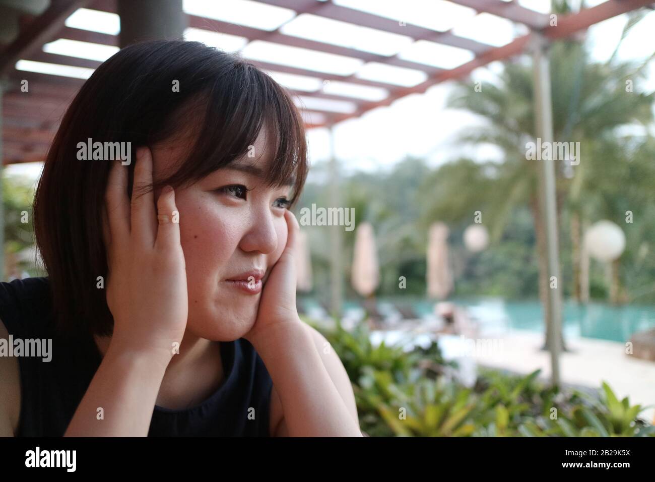 Eine schöne Dame, die sich in einem Restaurant am Pool entspannen kann. Stockfoto