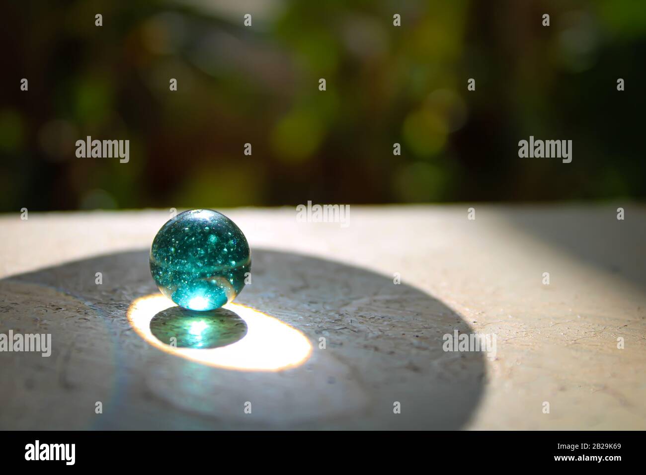 Ein transparentes Glas mit grünen Murmeln auf der Oberseite der Wand mit einem guten Weichzeichnungshintergrund und einem kreativen Konzept und Textbereich Stockfoto