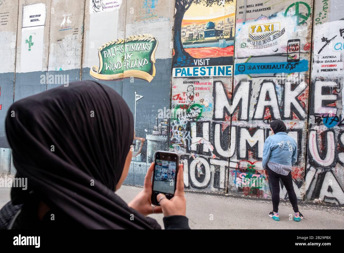 Junge Frauen fotografieren Kunstwerke an der Trennwand in Bethlehem, Palästina Stockfoto