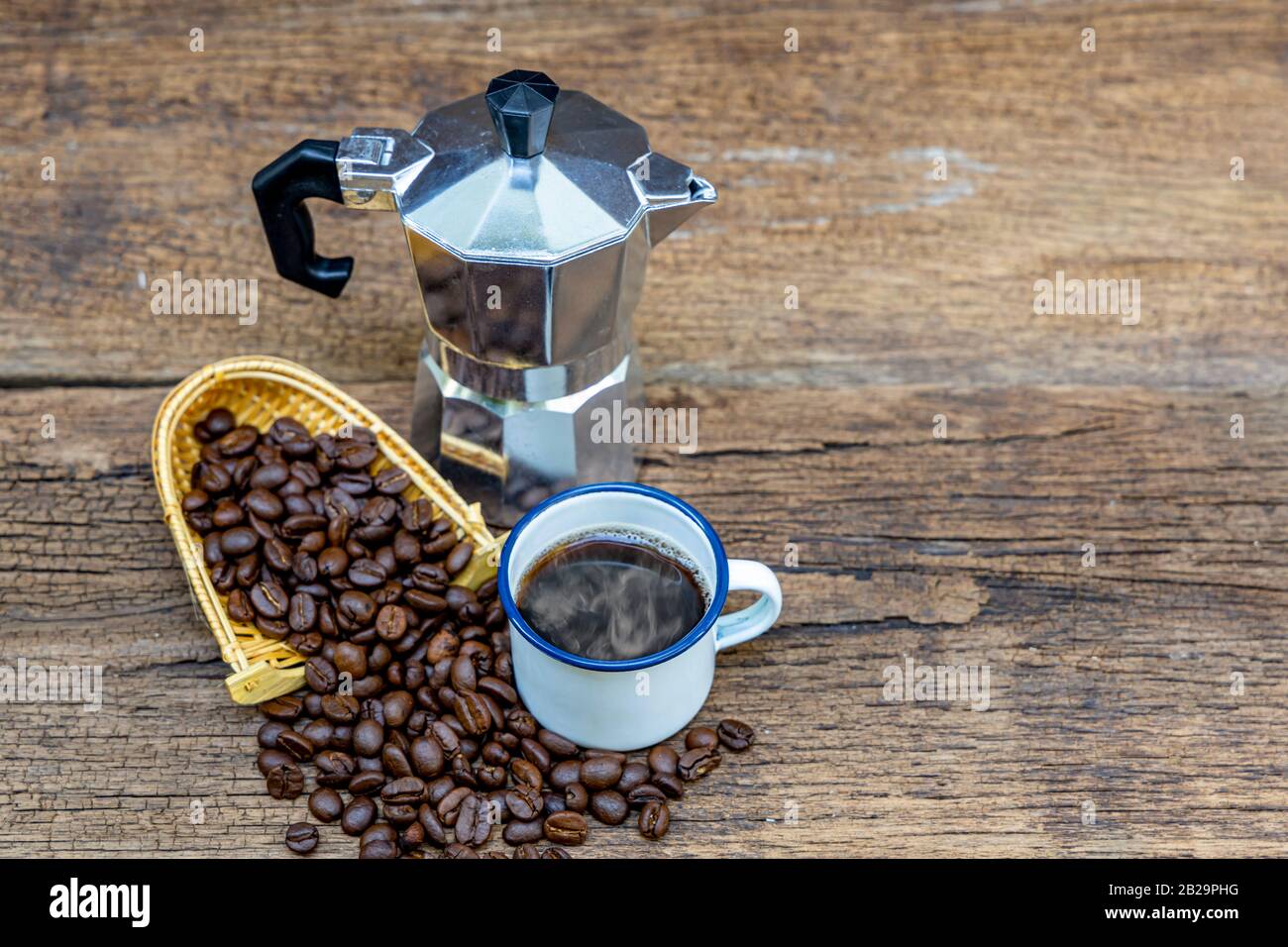 Eine weiße Zinn Tasse heißen Kaffee mit italienischer Kaffeekanne (Moka) und Kaffeebohnen auf Holztisch. Stockfoto