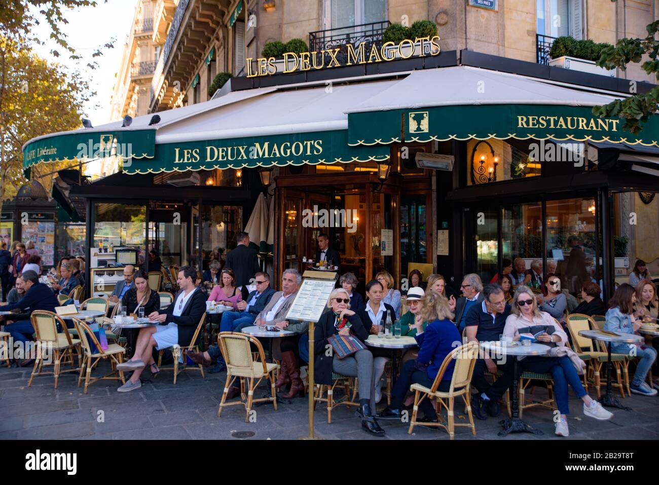 Leute, die auf Sitzplätzen im Freien in Les Deux Magots, einem berühmten Café in Paris, Frankreich, Kaffee trinken Stockfoto