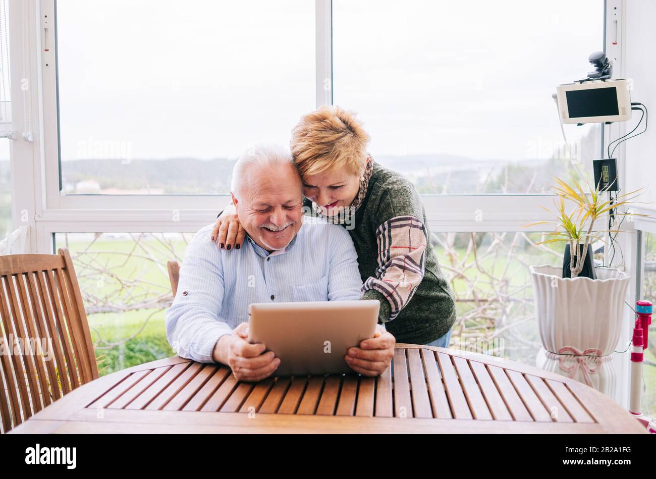 Ein reifes Paar, das zu Hause auf ein digitales Tablet blickt Stockfoto