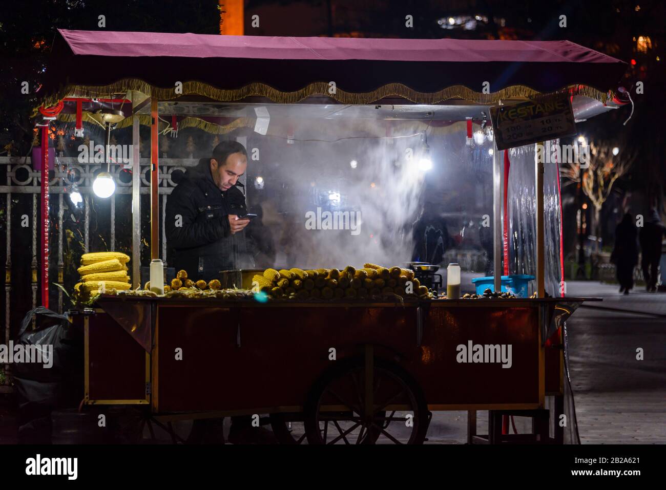 Straßenhändler, der geröstete Kastanien und Zuckermais aus einem Stand in der Nacht verkauft, Istanbul, Türkei. Stockfoto