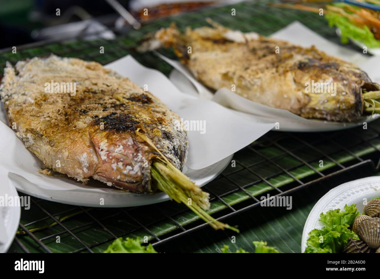 Gesalzene Fische mit Zitronengras, die auf einem Grillgrill in einem Straßenrestaurant, Bangkok, Thailand, gekocht werden Stockfoto