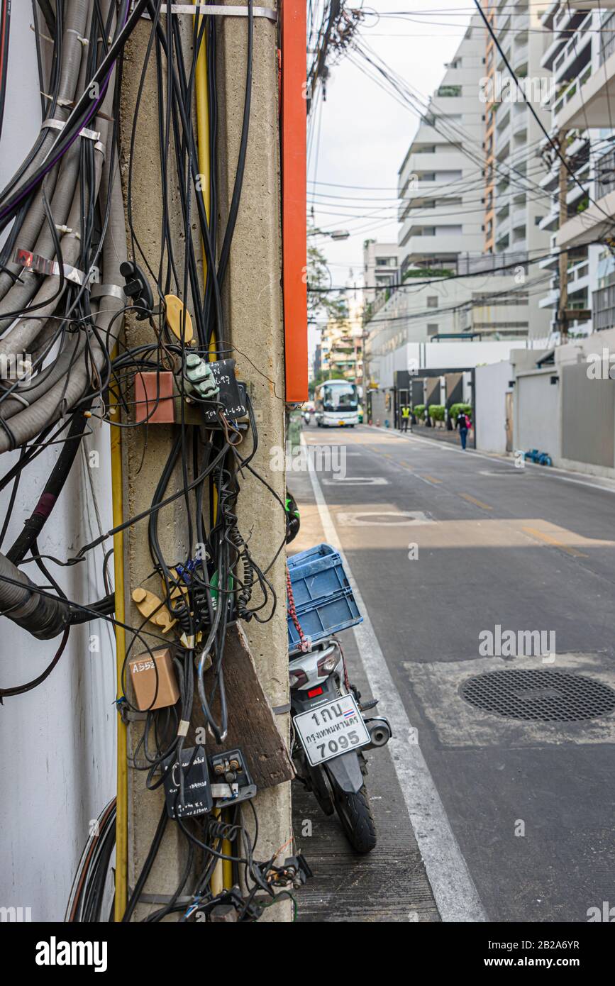 Unordentliche und unsaubere elektrische Kabel, die an einem Strompfosten in Thailand hängen Stockfoto