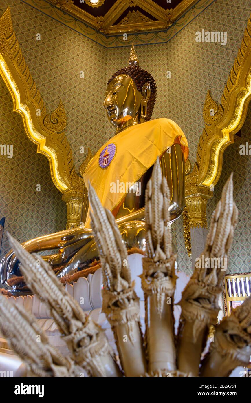 Aus Keramik geschnitzte mehrköpfige Schlange vor einer goldenen Statue des Buddha mit einer Safrangarbe im verzierten Wat Songkhram, Bangkok, Thailand Stockfoto