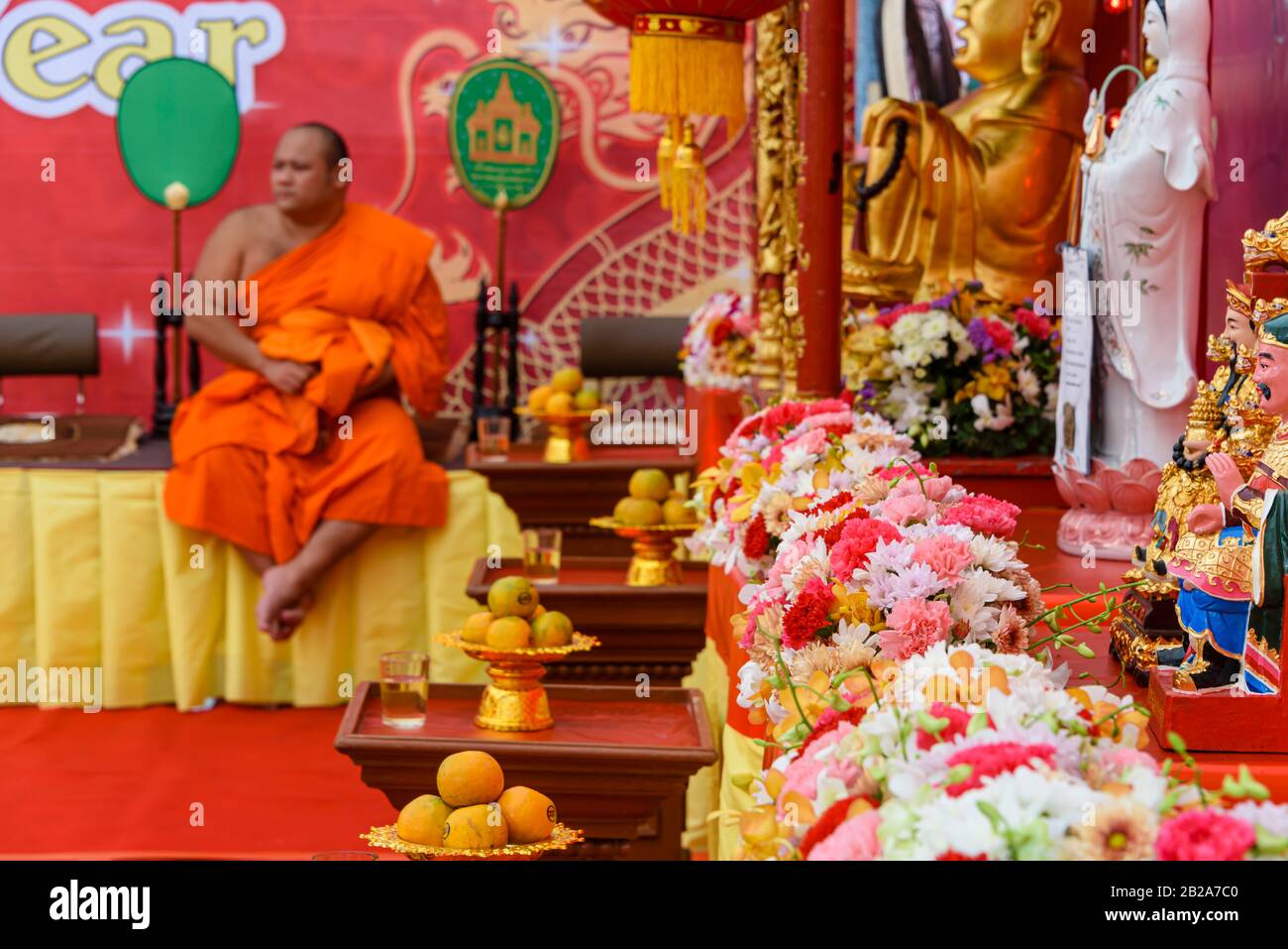 Ein buddhistischer Mönch sitzt hinter einem Blumenarrangement bei der chinesischen Lunar-Neujahrsfeier 2020, Wat Pho, Bangkok, Thailand Stockfoto