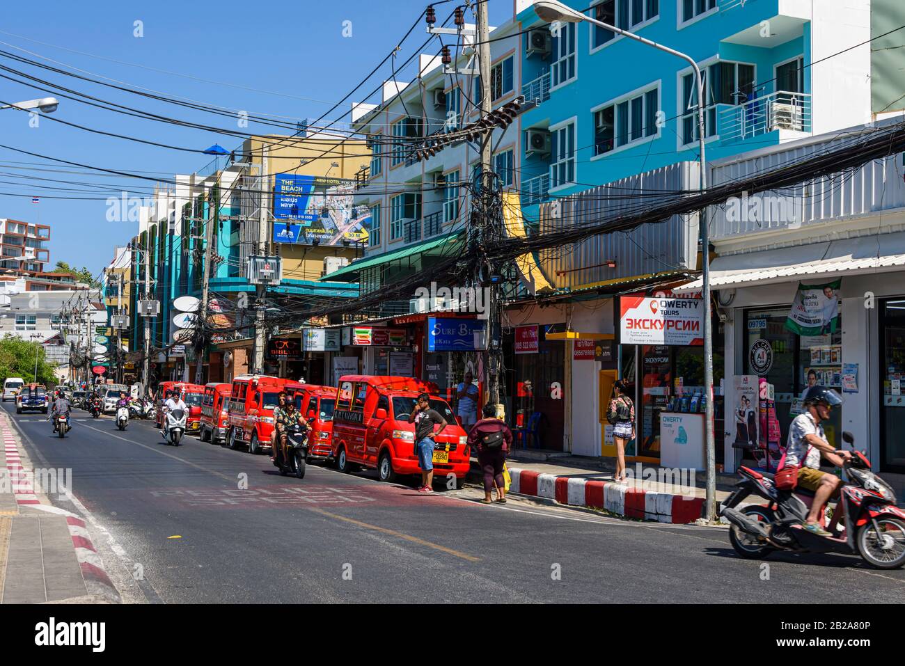Tuk Tuks parkten auf der Seite der Straße, unter unordentlichen und unsauberen elektrischen Kabeln, die an einem Strompfosten in Thailand hängen Stockfoto