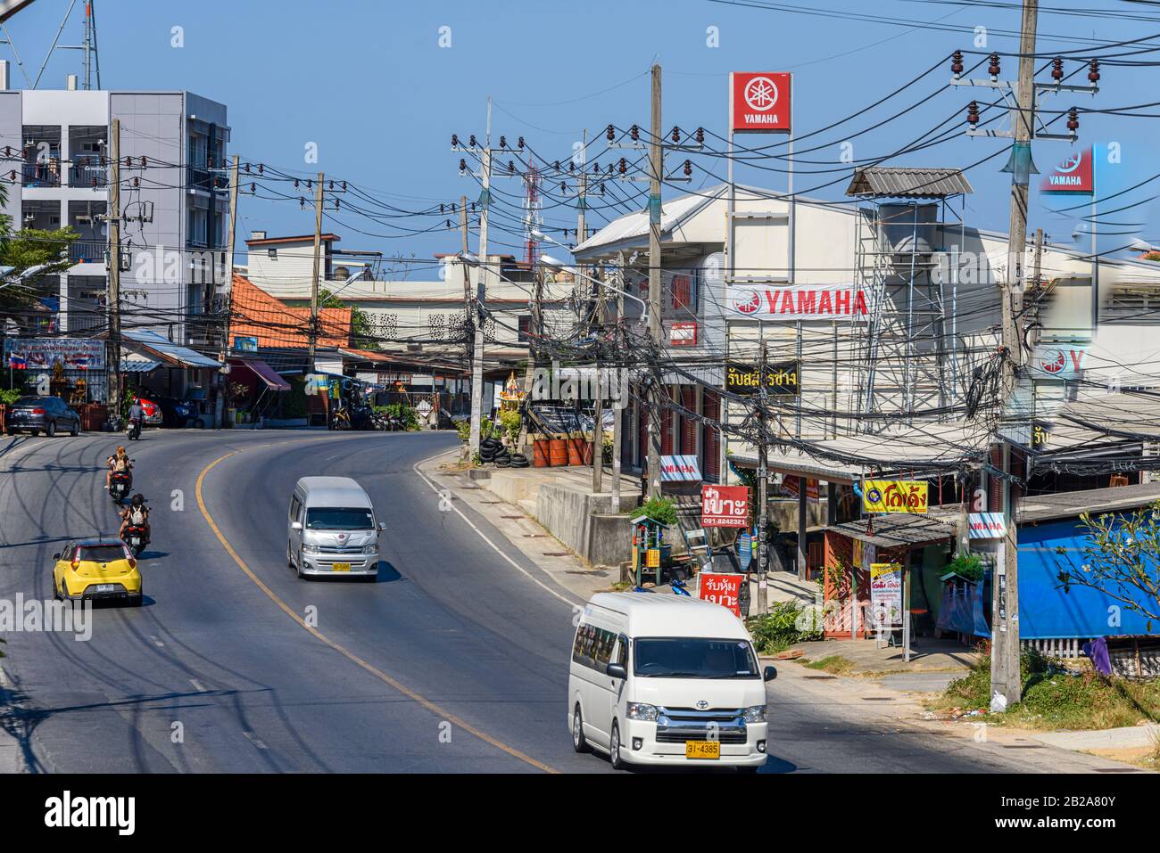 Verkehr auf der Straße mit unordentlichen und unsauberen elektrischen Kabeln, die an einem Strompfosten, Kata, Thailand, hängen Stockfoto