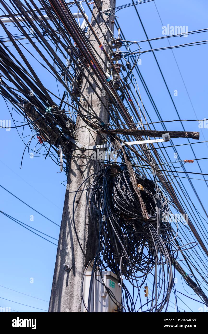 Unordentliche und unsaubere elektrische Kabel, die an einem Strompfosten in Thailand hängen Stockfoto