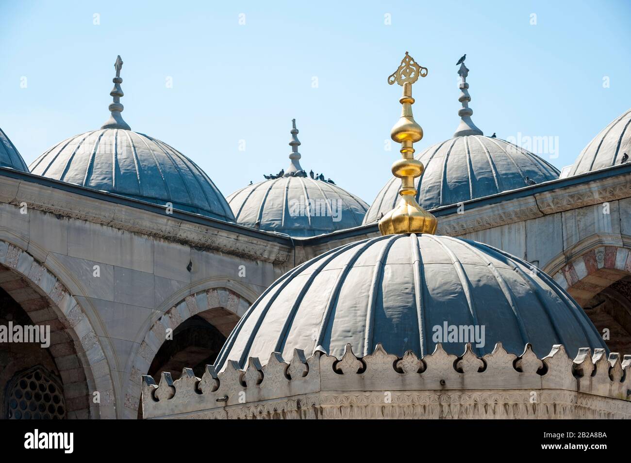 Dramatischer, sonnenbeleuchteter Blick auf die verwitterten Kuppeln einer Blauen Moschee unter hellblauem Himmel in Istanbul, Türkei Stockfoto