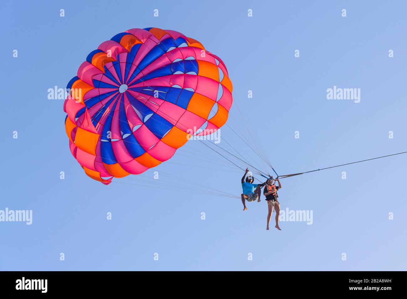 Tourist zog in einen Tragegurt, der an einem Fallschirm befestigt war, während ein Thailänder auf den Saiten sitzt, während sie parascend parascend, Patong Beach, Phuket, T Stockfoto