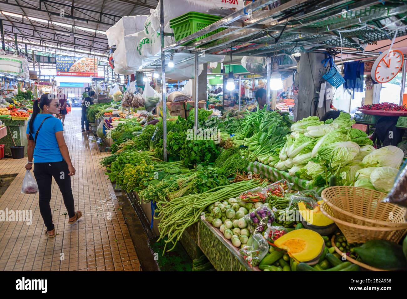 Eine Frau betrachtet einen Gemüsestall, der auf dem traditionellen Mae Somchit Kata Fresh Market, Kata, Phuket, Thailand, verkauft wird Stockfoto