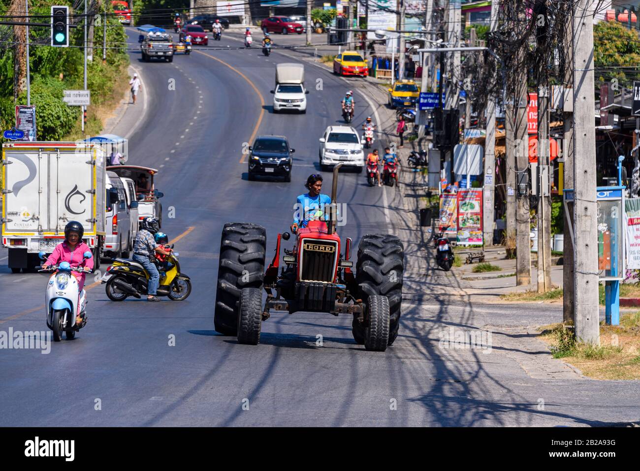 Ein alter Ford-Traktor fährt im Verkehr auf einer typischen Straße in Kata Dorf, Phuket, Thailand Stockfoto