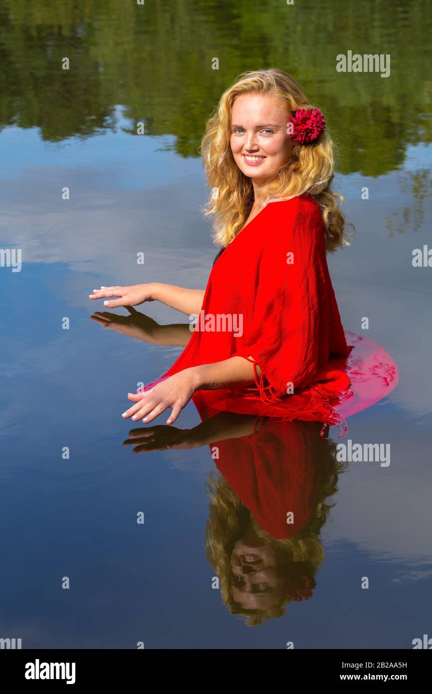 Portrait junge blonde europäische Frau steht in natürlichem Wasser Stockfoto