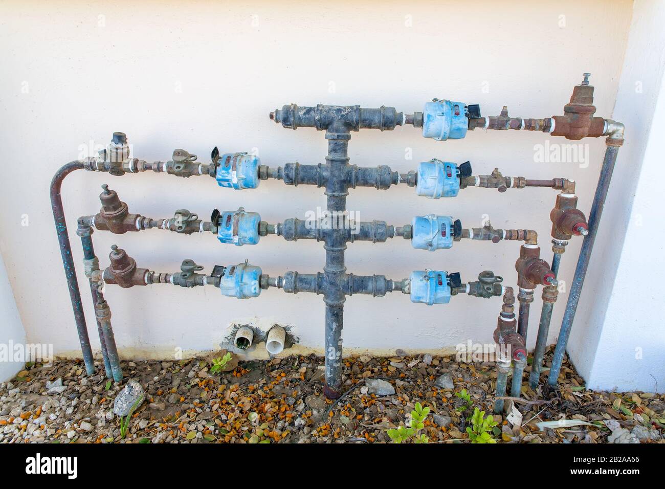 Wasserleitungen mit Wasserhähnen und Wassermessern an der Hauswand Stockfoto