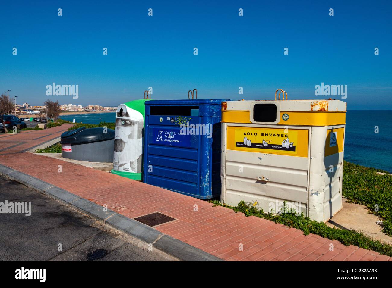 Bunte Recycling-Mülltonnen in der Nähe des Meeres unter blauem Himmel, Torrevieja, Costa Blanca, Spanien Stockfoto