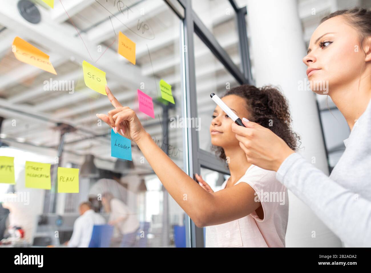 Business Leute, die im Büro und Post-it Notizen Idee zu teilen. Brainstorming Konzept. Haftnotiz auf einer Glaswand. Stockfoto