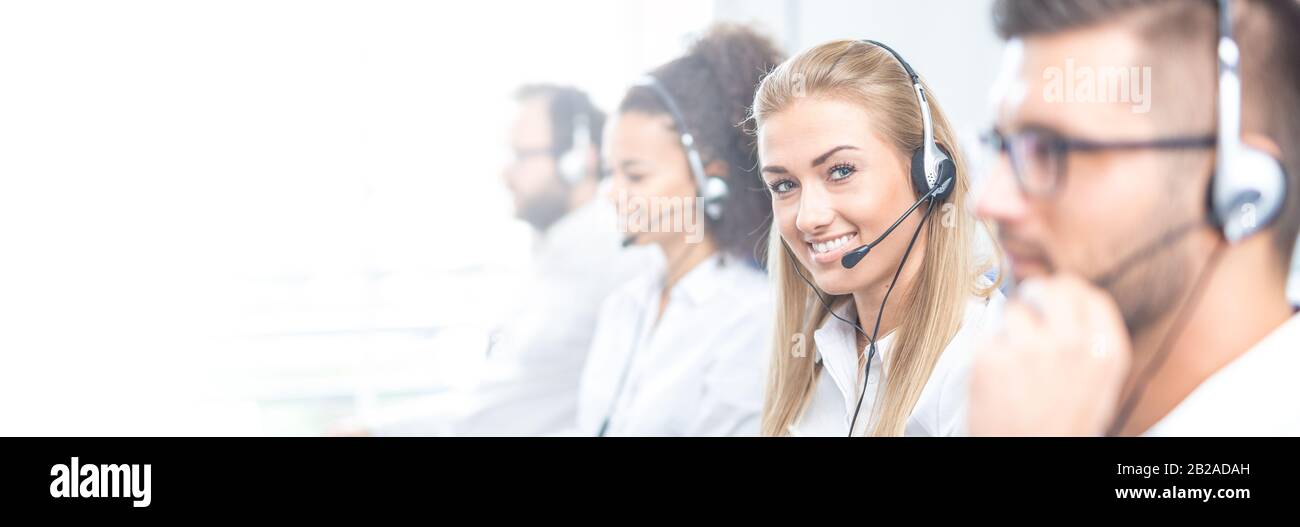 Call Center Mitarbeiter durch ihr Team begleitet. Lächelnd customer support Operator bei der Arbeit. Junge Mitarbeiter mit einem Headset. Stockfoto