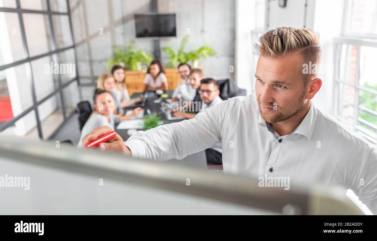 Business Coach. Der Teamleiter unterrichtet die Mitarbeiter bei einem Geschäftstreffen in einem Konferenzraum. Stockfoto