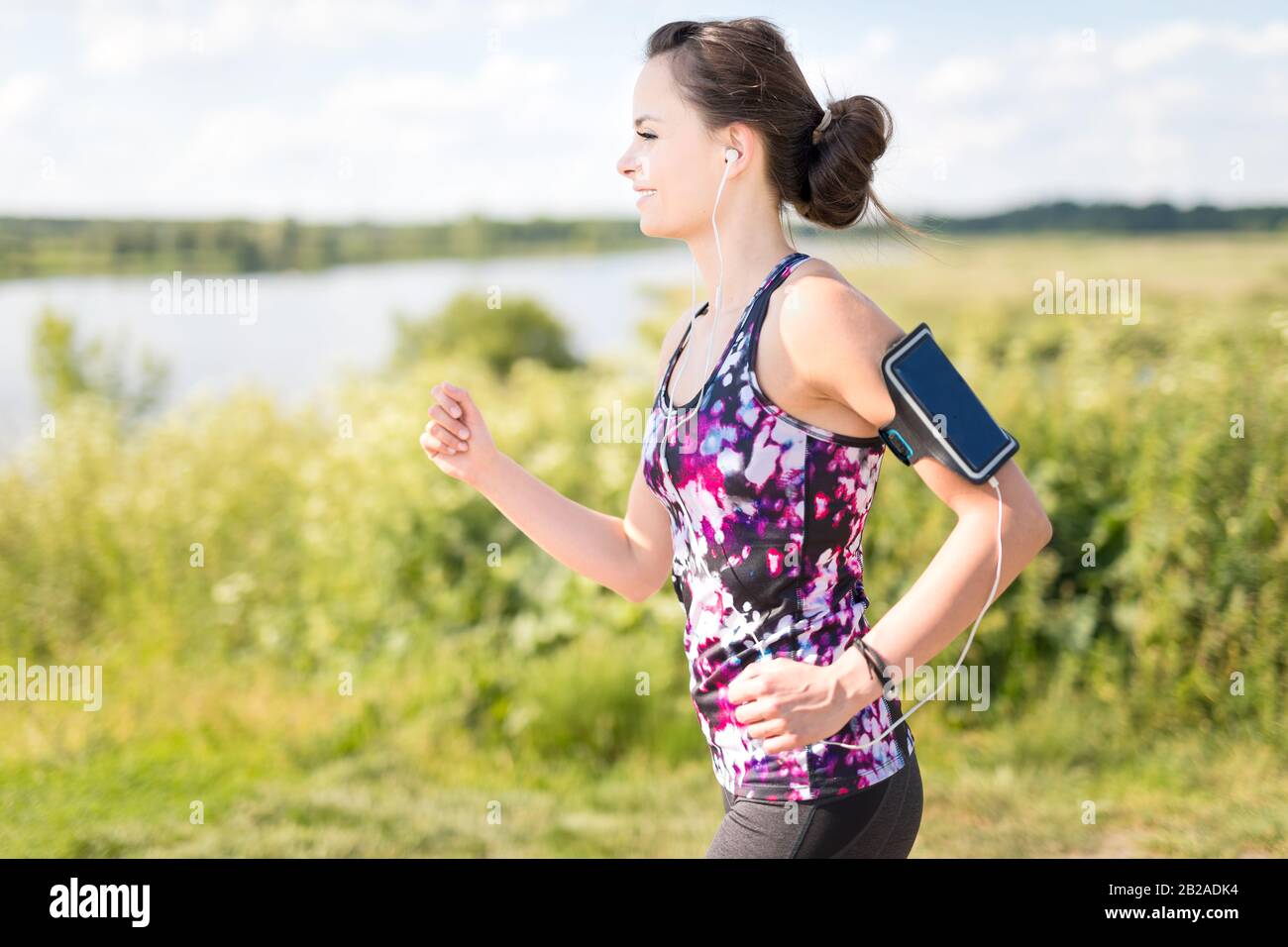 Schöne, junge Frau, die auf dem Wasser an der Landstraße läuft. Jogging-Konzept. Stockfoto